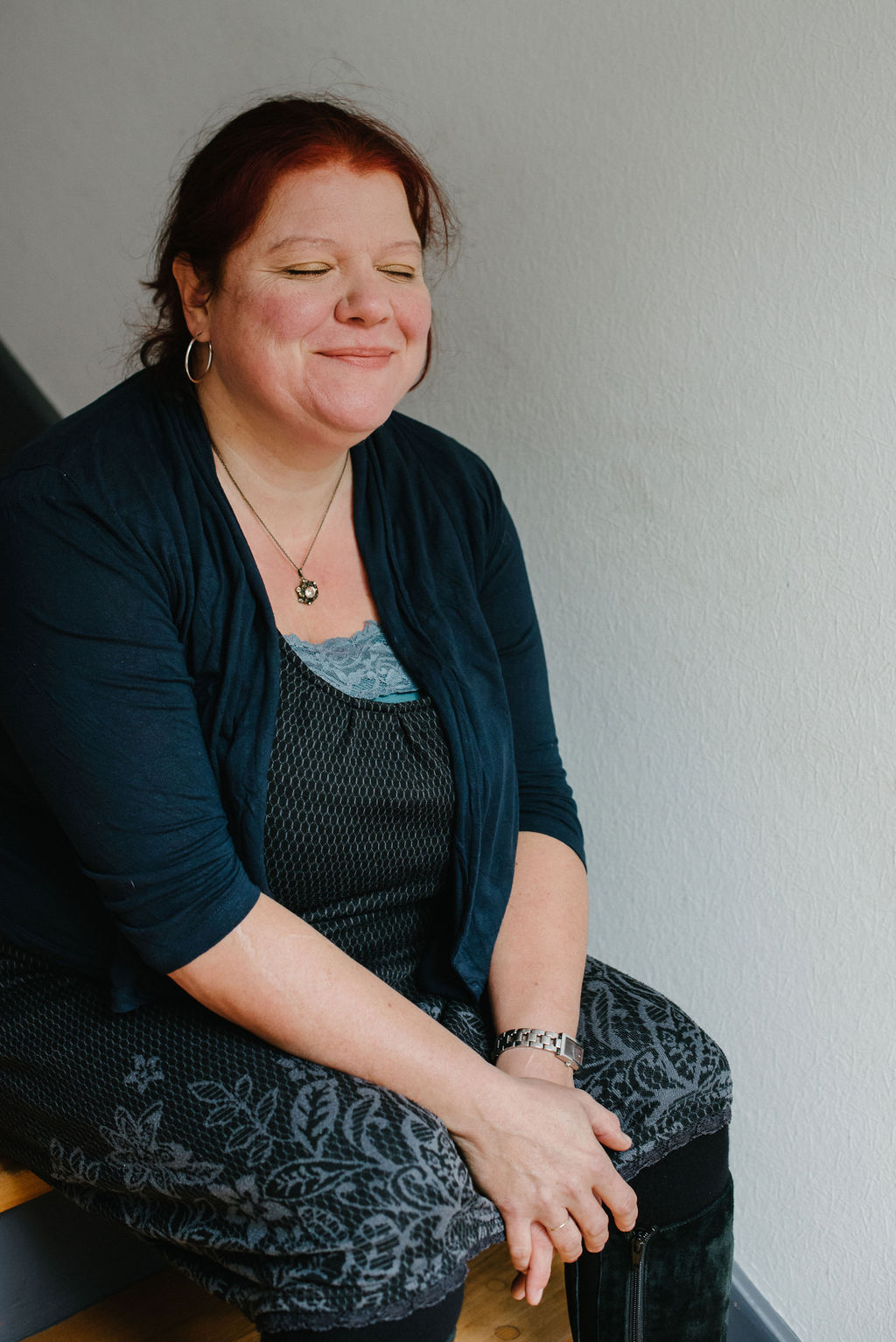Natalie sitzt auf einer Treppe, hat entspannt die Augen geschlossen und lächelt